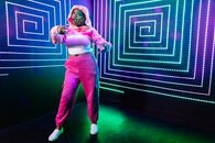 Woman in Pink Long Sleeve Shirt and Blue Pants Standing on Green and Black Floor