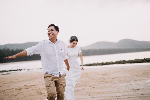 Free A bride and groom joyfully run on a beach in Hồ Chí Minh, capturing their love and happiness. Stock Photo
