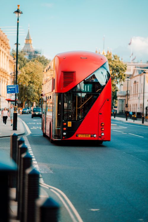 Free Red double-decker bus traversing a vibrant London street on a clear day. Stock Photo
