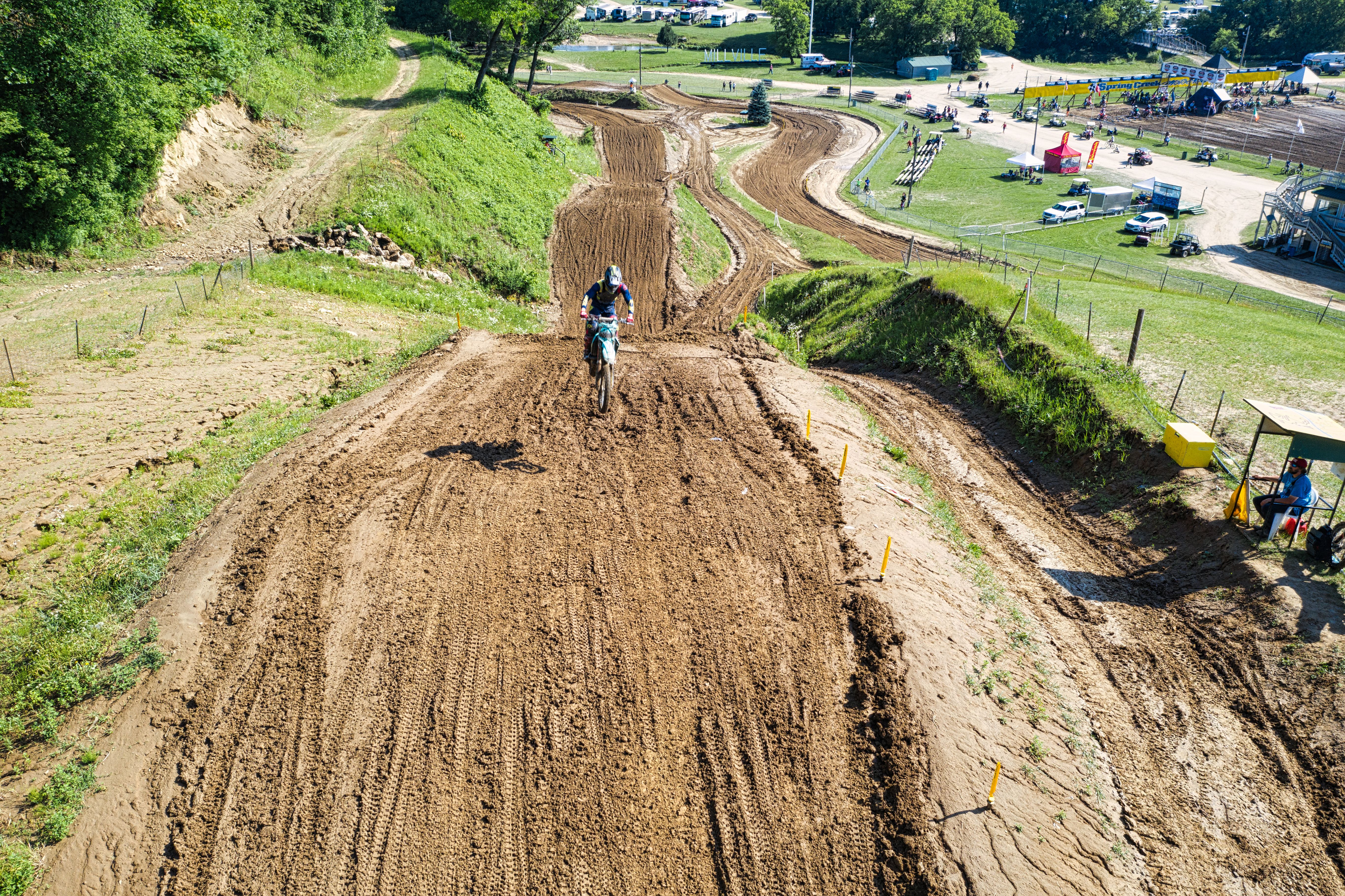 Aerial view capturing a thrilling motocross race on a dirt track in Millville, MN, surrounded by nature.
