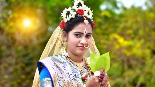 Free Portrait of a smiling Bengali woman in traditional bridal attire with a flower crown, outdoors in natural sunlight. Stock Photo