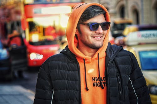 A Man in Orange Hoodie Smiling while Wearing Black Puffer Jacket