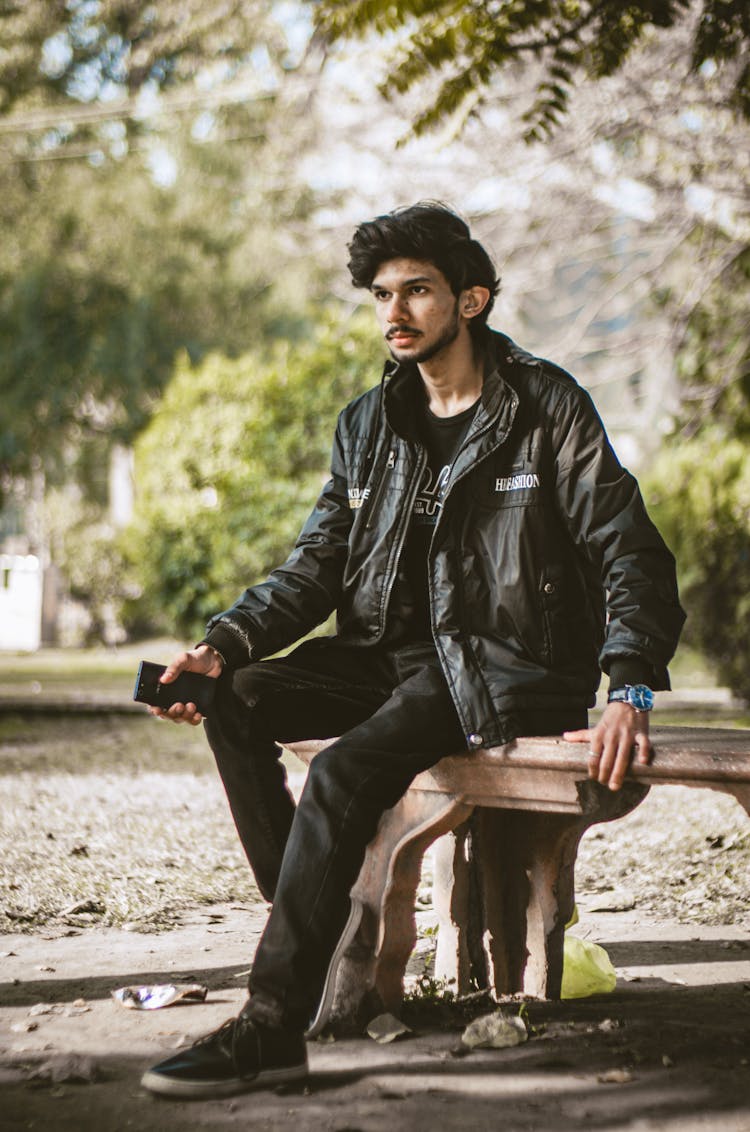 Man In Black Leather Jacket Sitting On Wooden Bench