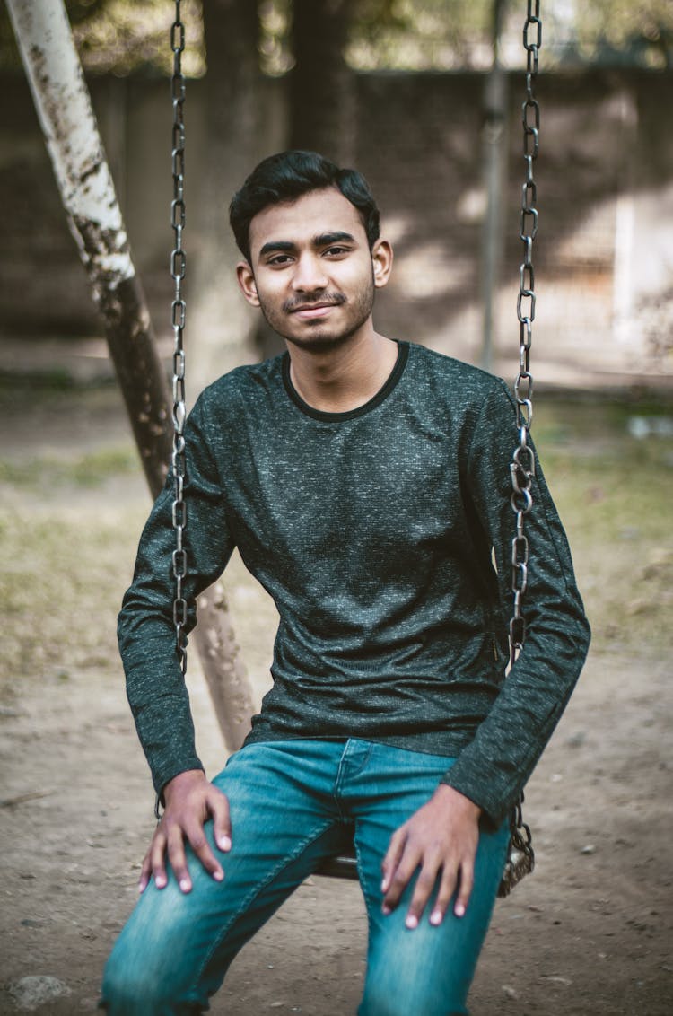 Man In Black Long Sleeve Shirt And Jeans Sitting On Swing