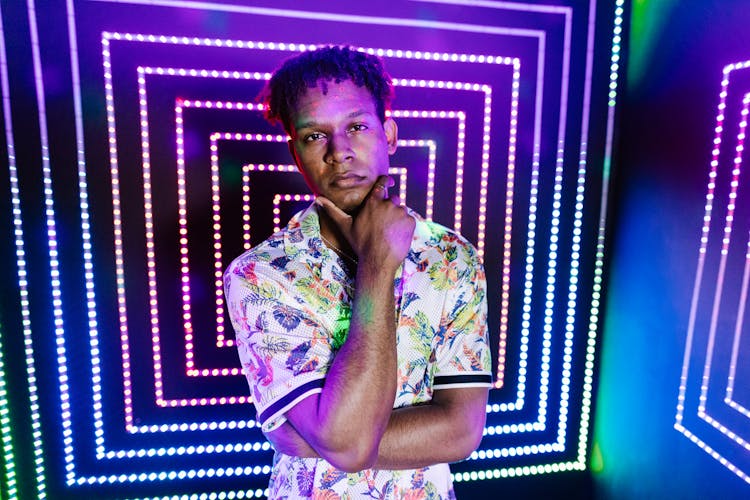 Man Standing In Printed Shirt Against Illuminated Lights On Wall