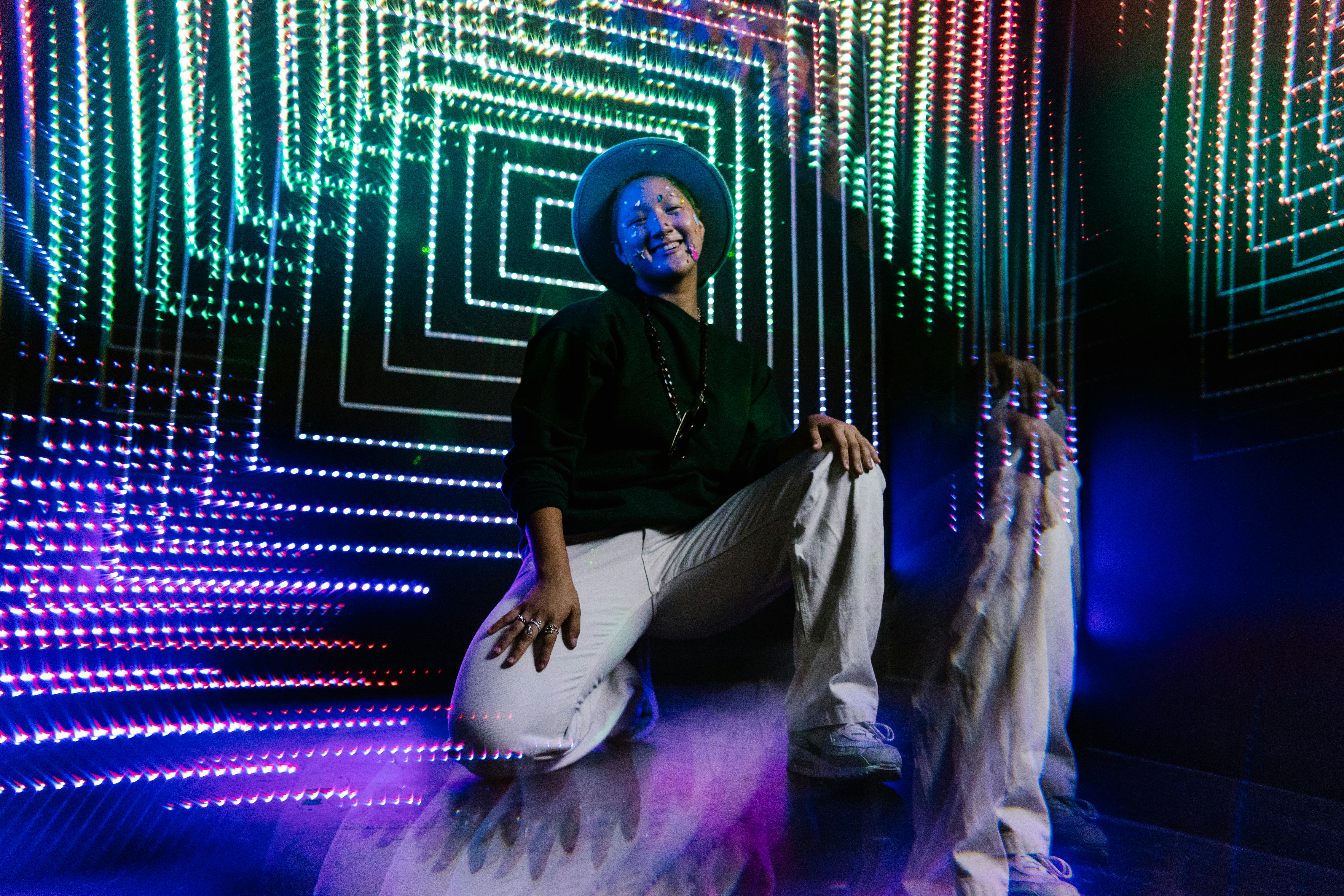 man in black long sleeve shirt and white pants sitting on purple and white floor