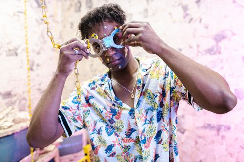 Free A man with handcuffs and face stickers in a colorful, artistic setting. Stock Photo