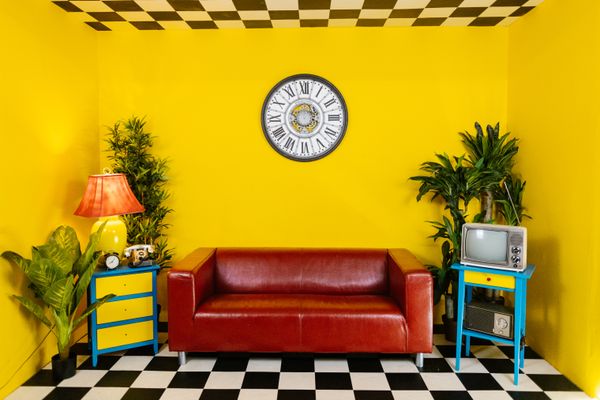 Retro yellow living room with a red couch and checkered floor — photo by RDNE Stock project on Pexels