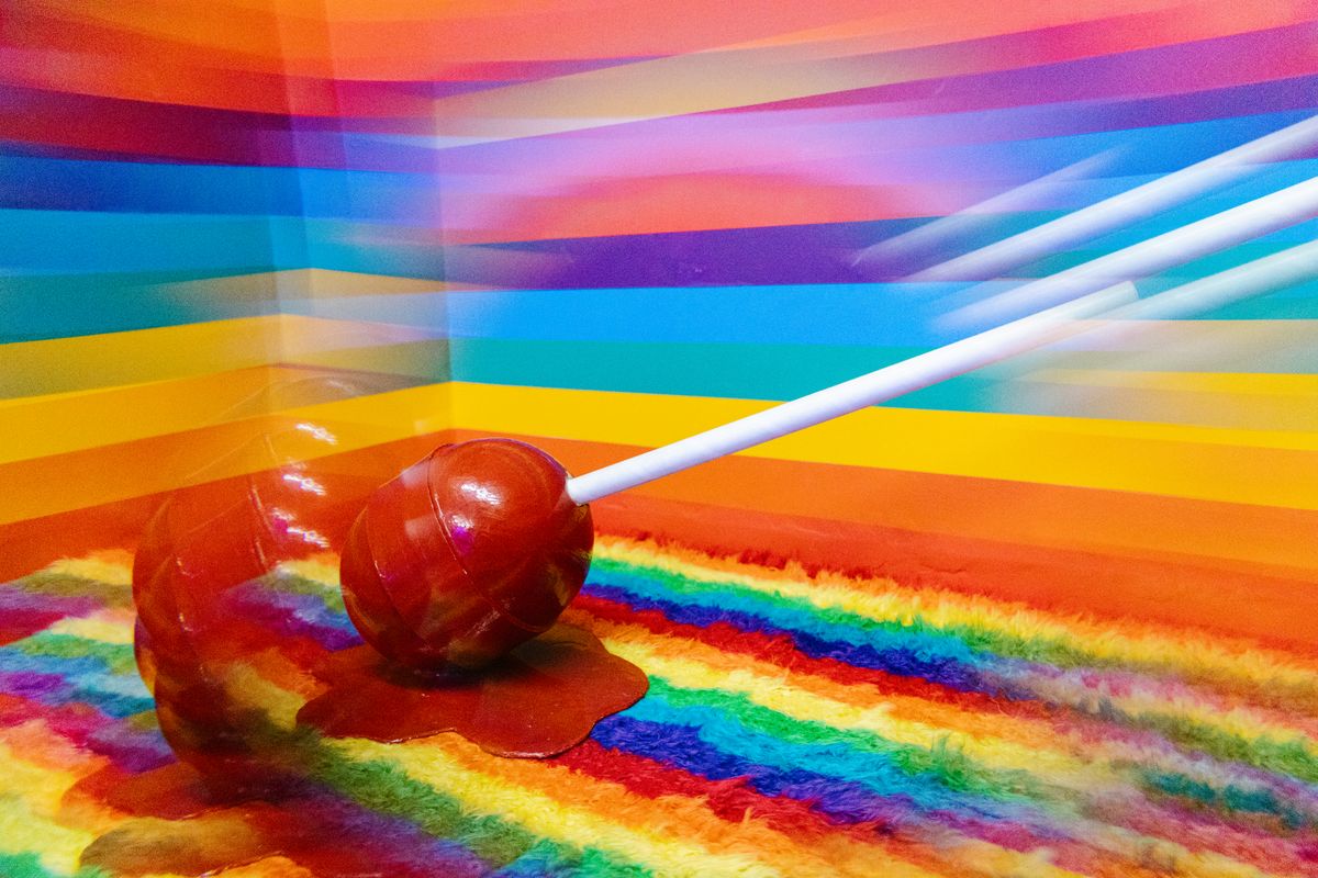 Colorful lollipop on a vivid rainbow background, melting slightly, evoking joy and childhood memories.