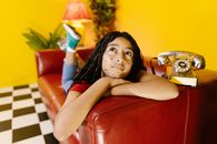 Woman in Black Tank Top Lying on Red Couch