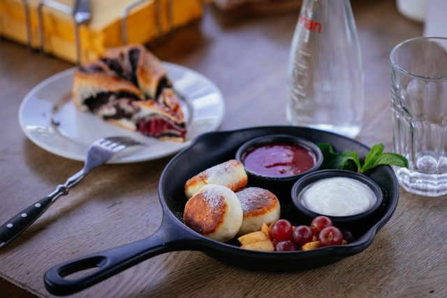 Enjoy a tasty breakfast featuring syrniki, fresh grapes, and berry dessert in a cozy setting.