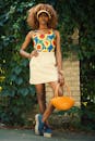 一位穿着向日葵连衣裙的别致女人，在郁郁葱葱的花园里背着橙色包