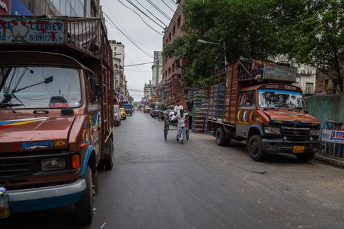 Free Vibrant street scene in India featuring colorful trucks, bicycles, and daily urban life. Stock Photo