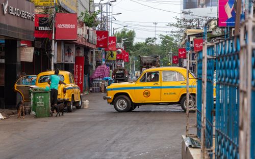 Free Vibrant street scene in Kolkata featuring classic yellow Ambassador taxis amidst lively urban ambiance. Stock Photo