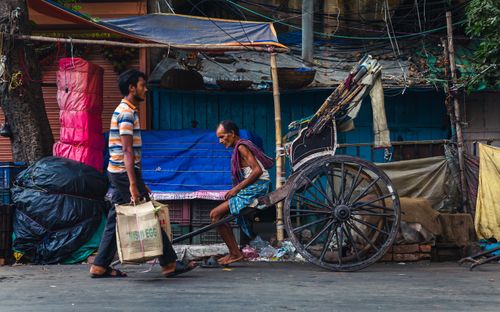Free A man walks past a traditional rickshaw in an urban street scene, capturing daily life. Stock Photo