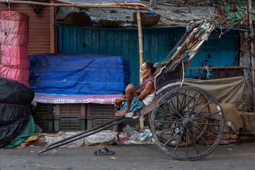 An elderly man rests in a rickshaw on an urban street, showcasing local culture.