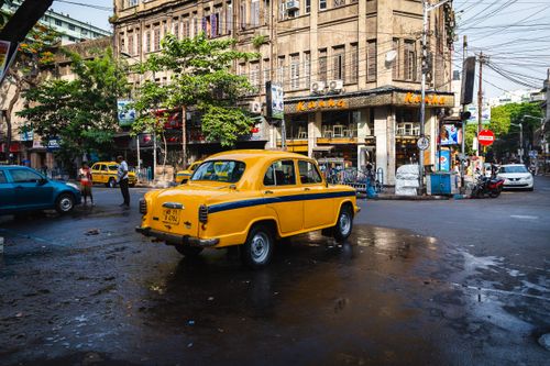 Free Vibrant city street scene featuring a classic yellow taxi in an urban setting with historic architecture. Stock Photo