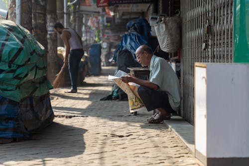 Elderly Man Sitting While Reading a Newspaper 