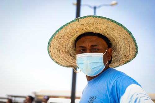 Free Close-up portrait of a man in a face mask and straw hat standing outdoors, emphasizing protection and style. Stock Photo