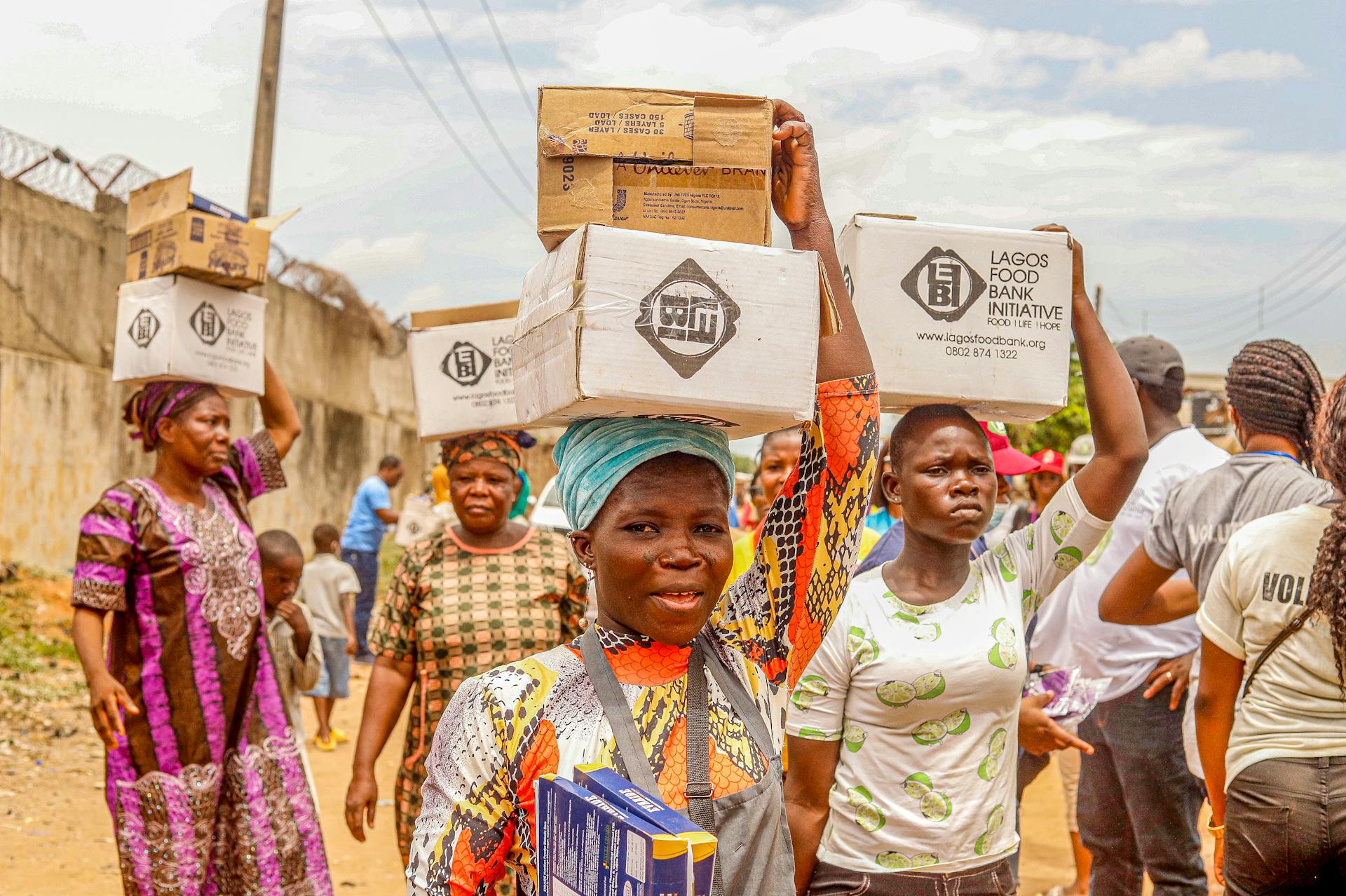 People carrying charity boxes during a community distribution event in Lagos.