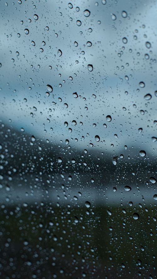Free Close-up of raindrops on glass, capturing a moody and serene atmosphere with a blurred outdoor background. Stock Photo