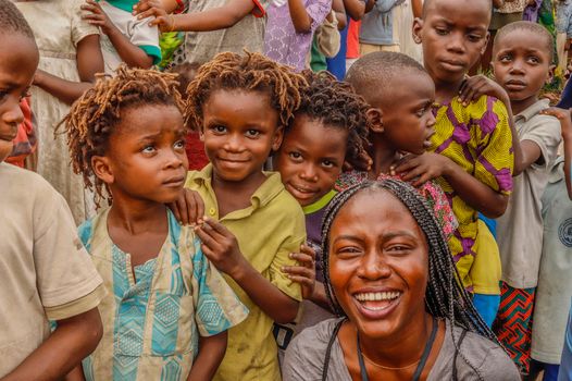 Cheerful children and woman smiling together outdoors, embracing joy.