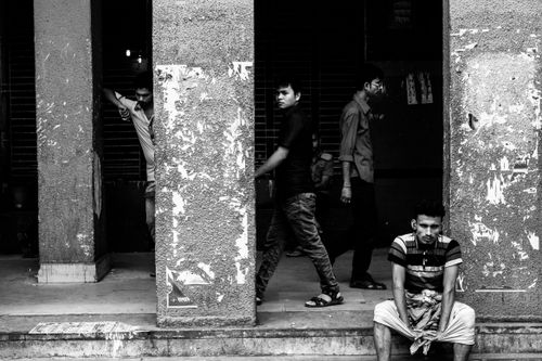 Free Black and white photo of young men sitting and walking near urban columns. Stock Photo