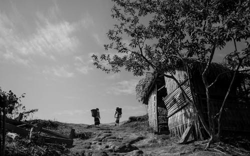 Grayscale Photo of People Walking near Wooden House