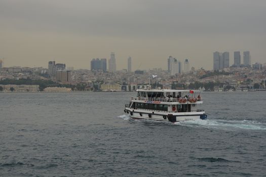 Passenger ferry sailing across the Bosphorus in Istanbul with city skyline in the background.