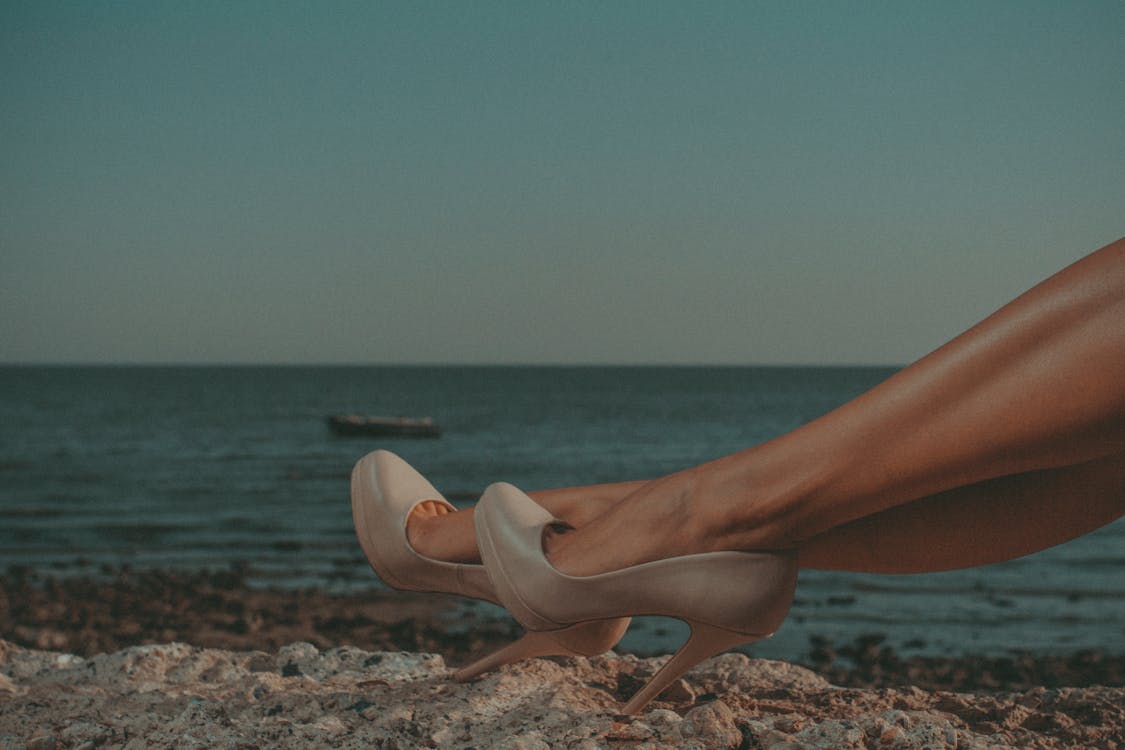 A Woman Wearing Heels on a Shore · Free Stock Photo