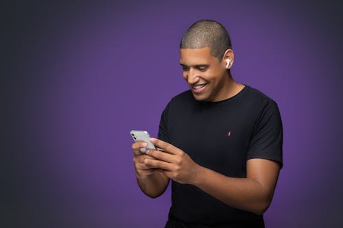 
A Man in a Black Shirt Using His Smartphone