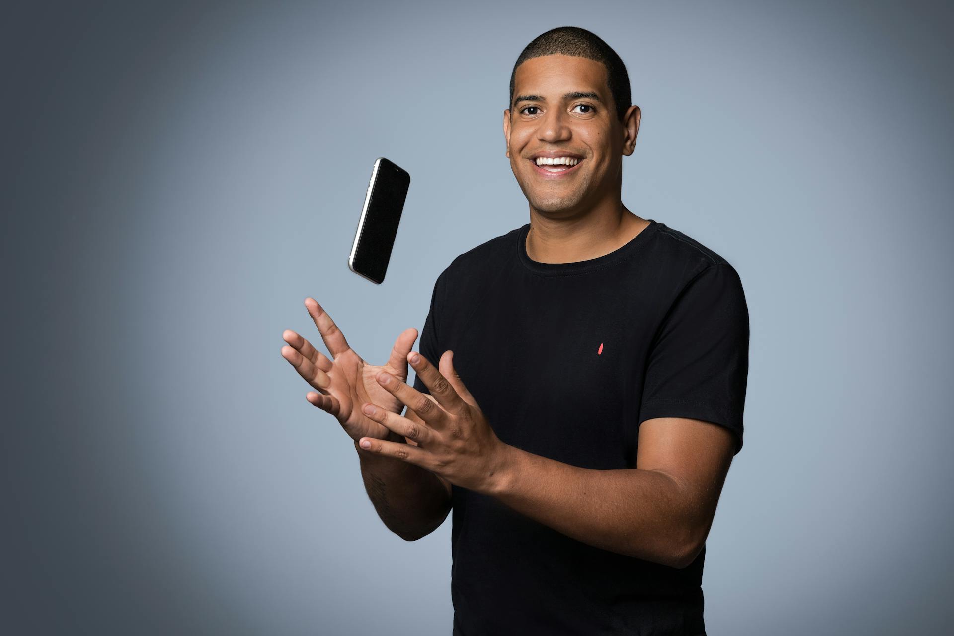 A Man in a Black Shirt Catching His Smartphone