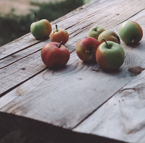 Green and Red Apples on Brown Wooden Surface