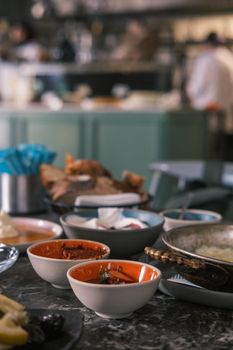 A collection of colorful ceramic bowls with various foods on a marble table in a warm kitchen setting.