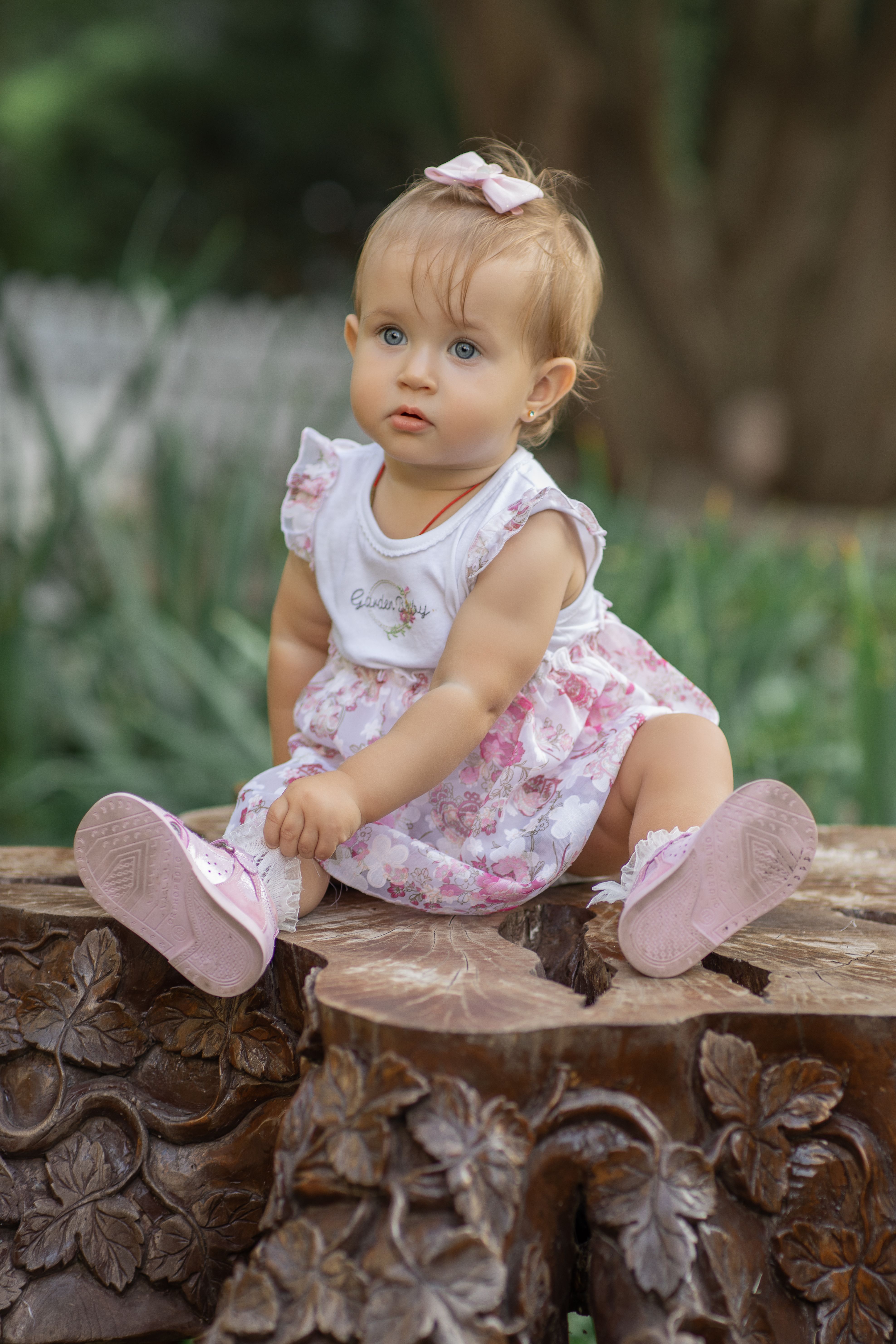 Charming toddler in a floral dress enjoying a sunny day outdoors.