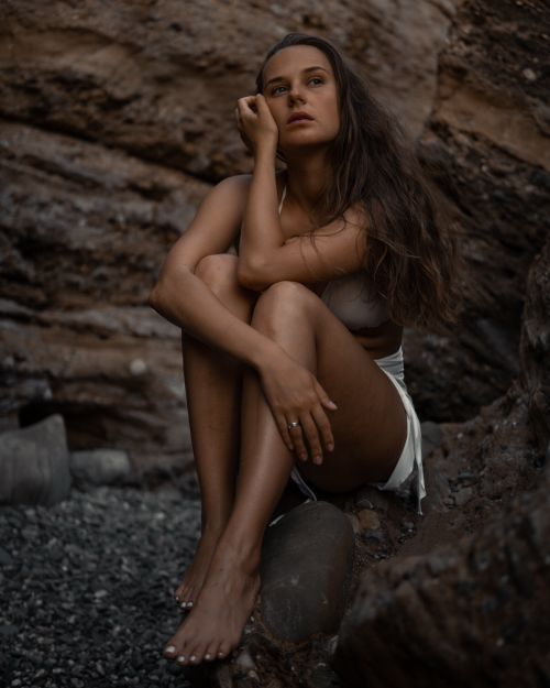 Free A woman sits barefoot on rocks, contemplating amidst a rugged outdoor setting. Stock Photo