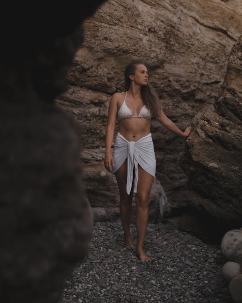 A Woman in White Bikini Top Standing Near the Rock Formation