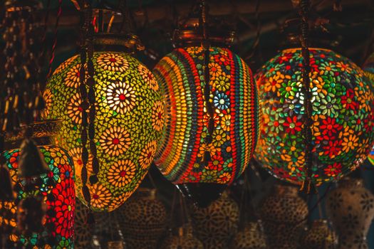 Colorful mosaic lanterns casting warm glow indoors, perfect for decoration.