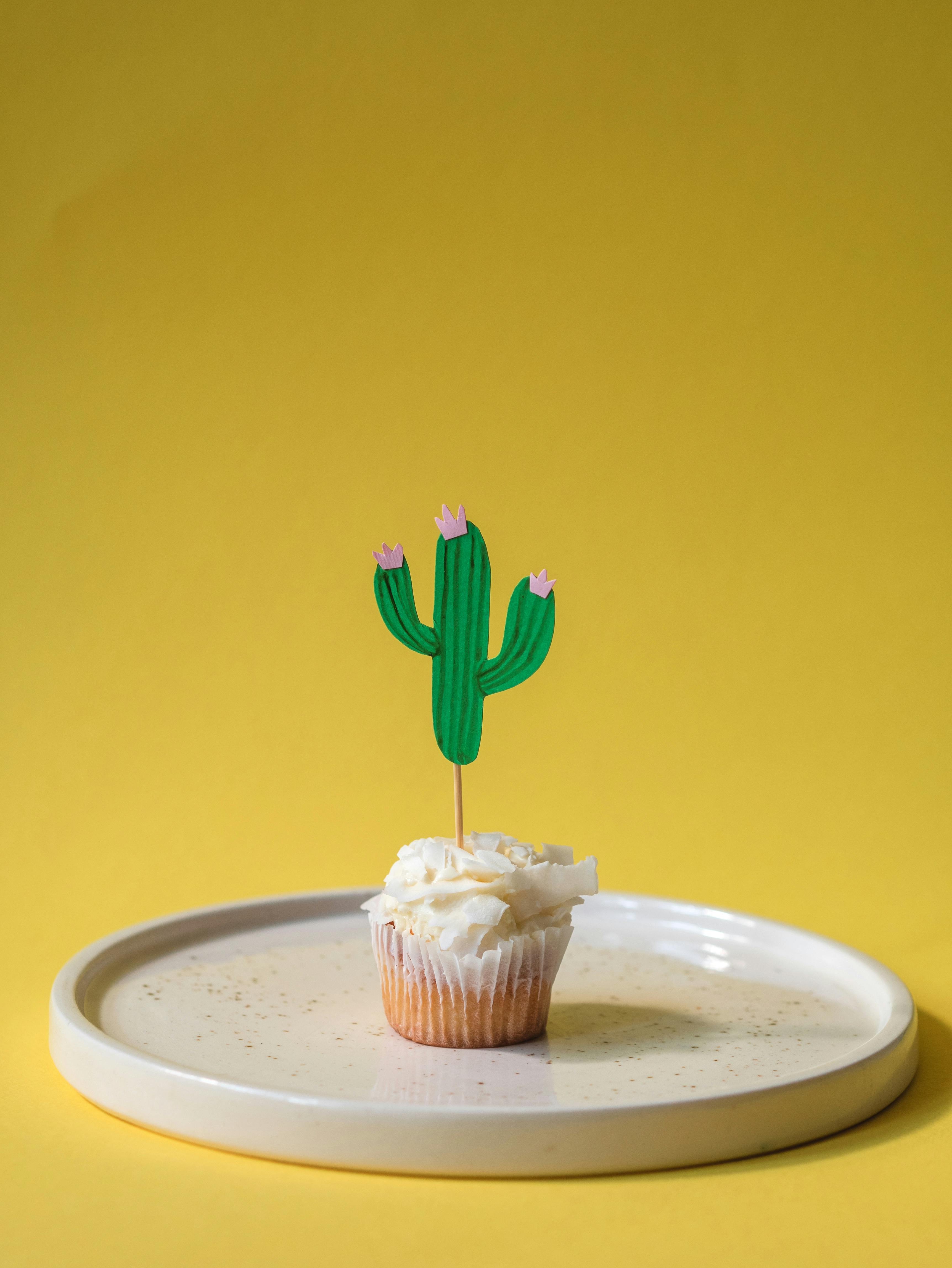 a cupcake with paper cactus on a plate