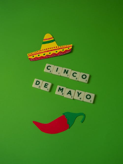 Cinco de Mayo Text on Green Background Beside Cutouts of Mexican Sombrero and Pepper