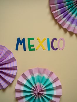 Vibrant paper art with 'Mexico' text and colorful fan designs on a soft background.