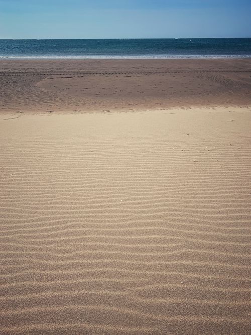 Free Peaceful beach scene in Huelva, Spain, showcasing sand, sea, and a clear summer sky. Stock Photo
