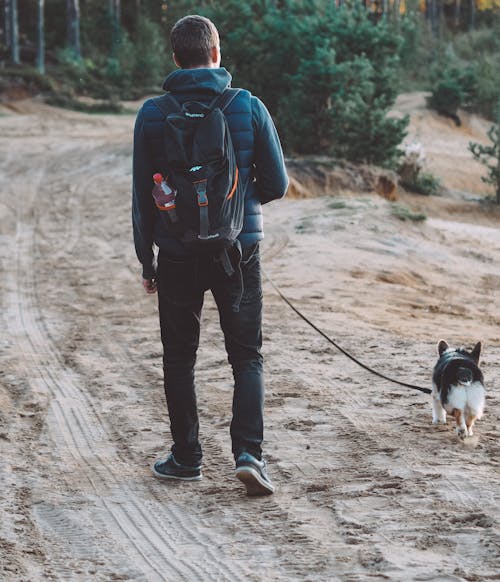 Free 

A Man Walking His Dog on an Unpaved Road Stock Photo