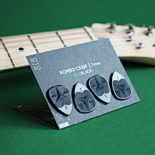 Free Close-up of Rombo brand guitar picks displayed with a guitar on a green background. Stock Photo