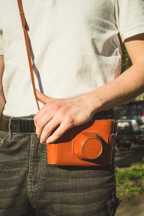 Free A Person Carrying a Camera with Leather Cover Stock Photo