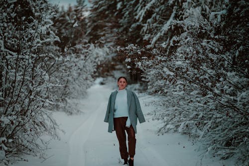 A Woman Standing between the Snow Covered Trees