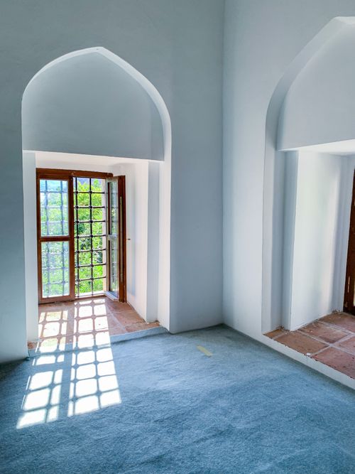 Free Sunlit room with arched doorways leading to a glass door, creating a serene indoor space. Stock Photo