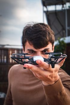 Close-up of a man holding a drone, ready to fly outdoors.