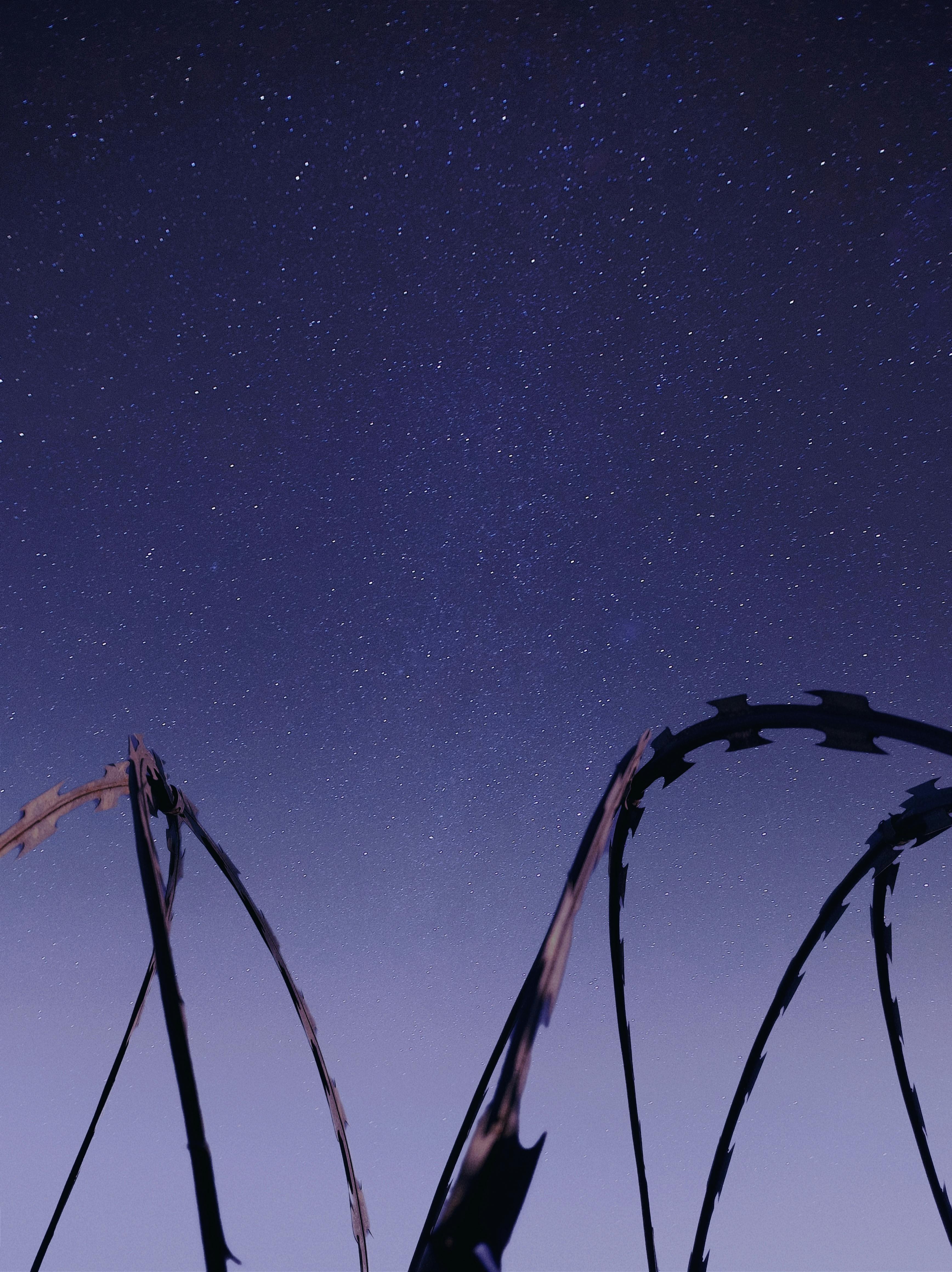 A dramatic view of a starry night sky over barbed wire in Jardinópolis, Brazil.