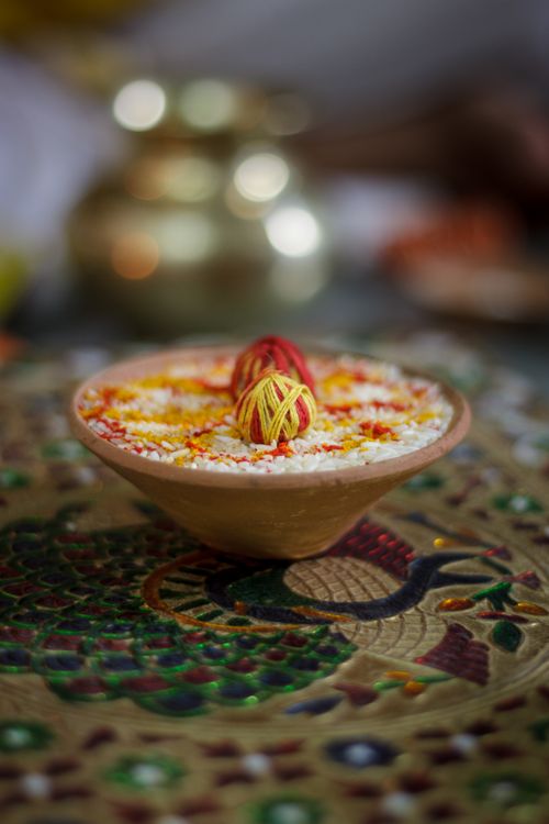 Free Colorful yarn rolls in a bowl with rice, set on ornate embroidery, creating a vibrant still life image. Stock Photo